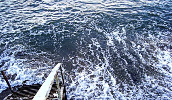 Descida de escada na água borbulhante do mar de inverno, mar Báltico no inverno . — Fotografia de Stock