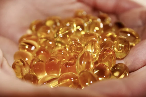 透明な黄色の錠剤の散乱 一握りの手のひらでカプセルのクローズ アップ 魚の油 オメガ カプセル 健康的なライフ スタイル 生理活性剤 栄養栄養補助食品 — ストック写真