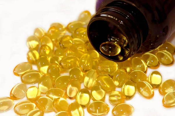 Cápsulas amarelas de gelatina omega 3 vertidas de frasco farmacêutico escuro . — Fotografia de Stock