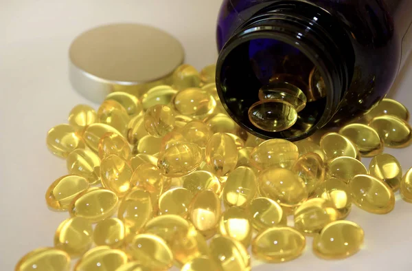 Žlutá želatinové kapsle omega 3 sype z temné láhve farmaceutické. — Stock fotografie