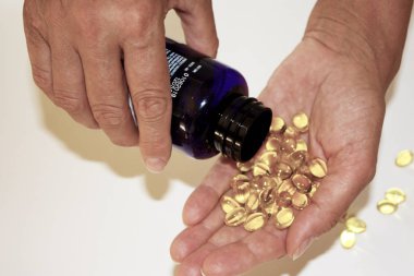 Yetişkin kadın kıdemli omega 3, yakın çekim şişe el Sarı kapsül dışarı dökülen.