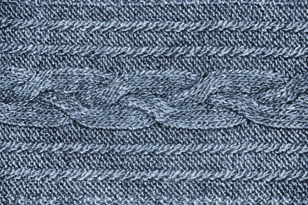 Knitted wool texture of jersey. Blue knitwear fabric with pigtail. Braid pattern for sweater, blanket. Woolen cloth, handmade knitting. Background for wallpaper and other elements of your design.