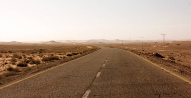 Otoyol Ürdün Çölü, elektrik direkleri asfalt yol Vadisi'nde, gündoğumu sonra vahşi sabahın erken saatlerinde boyunca.