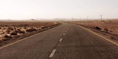 Otoyol Ürdün Çölü, elektrik direkleri asfalt yol Vadisi'nde, gündoğumu sonra vahşi sabahın erken saatlerinde boyunca.