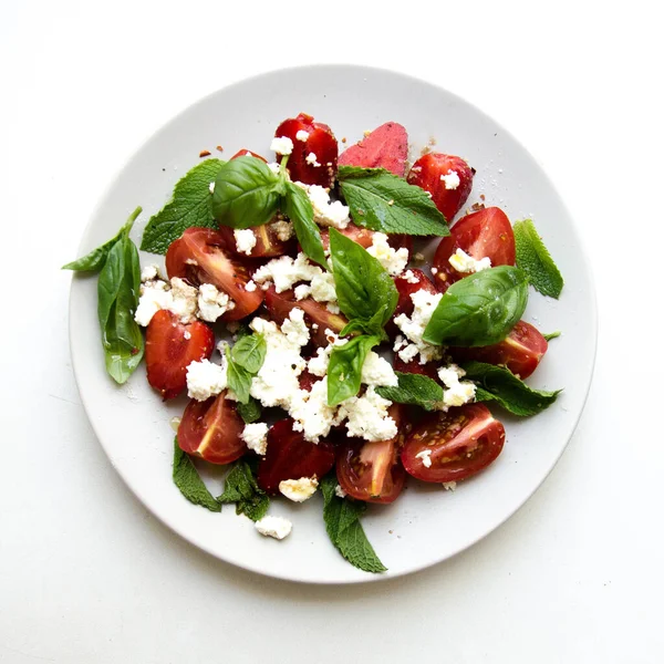 Summer salad with tomatoes, strawberry, green basil, and white cheese stock photo