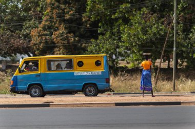 Bissau, Gine Cumhuriyeti - 31 Ocak 2018: bir tepsi kafasını ve Gine Bissau, Batı Afrika halk otobüsü (toca toca) bir kadınla Bissau şehir sokak sahne