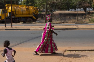 Bissau, Gine Cumhuriyeti - 31 Ocak 2018: şehir Bissau, Gine Bissau, Batı Afrika bir sokakta yürüyen bir renkli elbise giyen bir kadın ile sahnede sokak