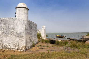 Cacheu, Bissau Cumhuriyeti - 1 Şubat 2018: ayrıntı Cacheu kale ve şehir Cacheu, Gine Bissau, limanda onun Kano hazırlanıyor bir balıkçı.