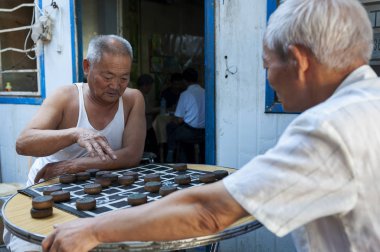 Dunhuang, Çin - 7 Ağustos 2012: İki Çince Çin satranç (Xiangqi) şehir Dunhuang, Çin'in bir sokakta adam