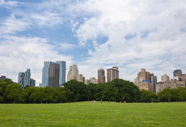 New York City, USA - June 6, 2010: People relaxing at the Central Park with the New York skyline in the background, in the city of New York, USA.