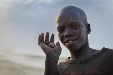 Orango Adası, Gine-Bissau 2 Şubat 2018: Günbatımında elinde Orango Adası plajda daraltan tutan genç bir çocuk portresi.