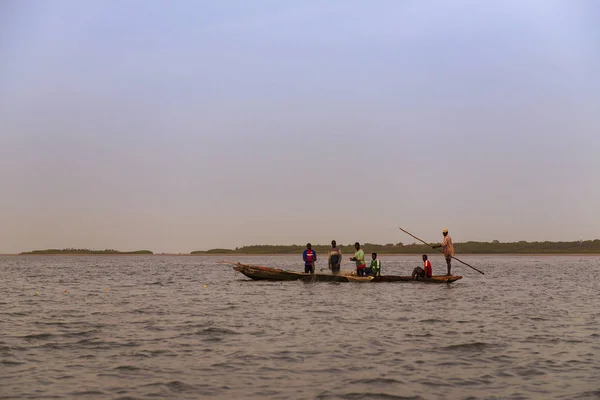 Orango Island, Guinea-Bissau - February 3, 2018: Fishermen collecting the nets in an old traditional fishing canoe near the island of Orango.