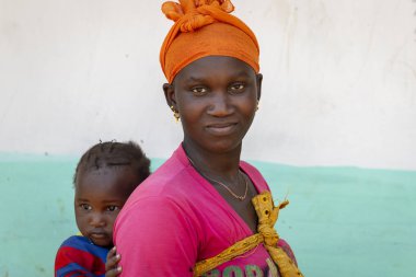 Gabu bölge, Bissau Cumhuriyeti - 7 Şubat 2018: bebek kızı onun omuzlarında, Gabu Region, Gine Bissau Mandina Mandinga Köyü taşıyan bir kadının portresi
