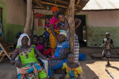 Gabu Region, Republic of Guinea-Bissau - February 7, 2018: Group of women and chldren in front of a home in the village of Mandina Mandinga in the Gabu Region, Guinea Bissau clipart