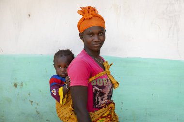 Gabu bölge, Bissau Cumhuriyeti - 7 Şubat 2018: bebek kızı onun omuzlarında, Gabu Region, Gine Bissau Mandina Mandinga Köyü taşıyan bir kadının portresi