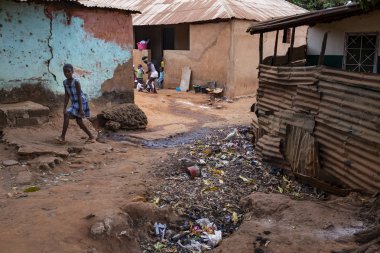Bissau, Gine Cumhuriyeti - 6 Şubat 2018: genç kız Bissau şehir, bir açık hava kanalizasyon ile mahallede bir kir sokakta Gine Bissau yürüyüş
