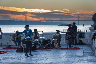 Lisbon, Portekiz - 11 Ocak 2012: Cais das Colunas Lizbon şehir Tagus Nehri ve arka plan, Portekiz köprüde Nisan 25 ile oynayan sokak müzisyenleri.