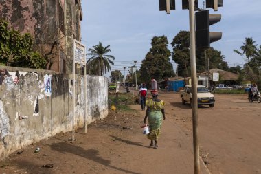 Bissau, Gine-Bissau Cumhuriyeti-8 Şubat 2018: Bissau kentinde sokak sahnesi, kafasına plastik bir konteyner taşıyan bir kadınla, Gine-Bissau, Batı Afrika
