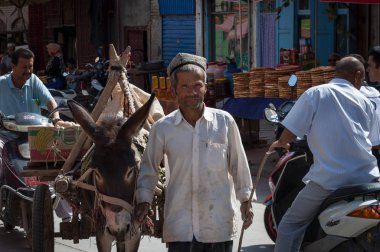 Kashgar, Xinjiang, Çin-14 Ağustos 2012: Uygur adam Kashgar, Xinjiang, Çin kentinde bir sokak pazarında bir eşek ile