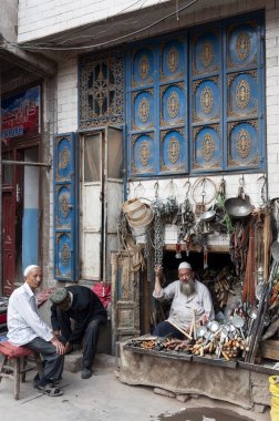 Kaşgar, Sincan, Çin - 14 Ağustos 2012: Kaşgar şehrinin bir sokakta bir mağazada Erkekler, Sincan, Çin