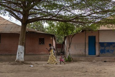Bissau, Gine-Bissau Cumhuriyeti - 8 Şubat 2018: Gine-Bissau, Batı Afrika'da Bissau şehrinde toprak bir sokakta yürüyen çocuklarıyla birlikte bir anne