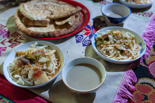 Traditional bowls of noodles on top of rugs on the floor in a Yurt by the Karakul Lake in Xinjiang, China
