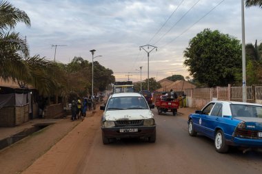 Bissau, Gine-Bissau Cumhuriyeti - 8 Şubat 2018: Bissau şehrinde gün batımında bir yolda araba ile sokak sahnesi, Gine Bissau.