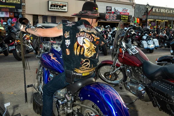 Sturgis, Güney Dakota - 9 Ağustos 2014: Yıllık Sturgis Motosiklet rallisi sırasında, Sturgis şehrinin ana caddesinde motosikletini park eden bir bisikletçi.