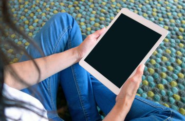 halı üzerinde oturan tablet kullanan kadın