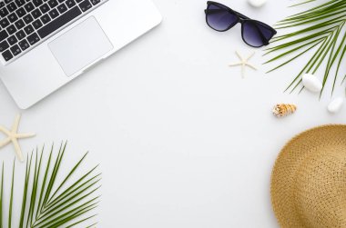 Yaz saati düz yatıyordu. İş ve seyahat kavramı. Dinlenme, deniz, Güneş, plaj ve iş. Çerçeve--dan laptop, yeşil yaprakları, güneş gözlüğü ve hasır şapka.