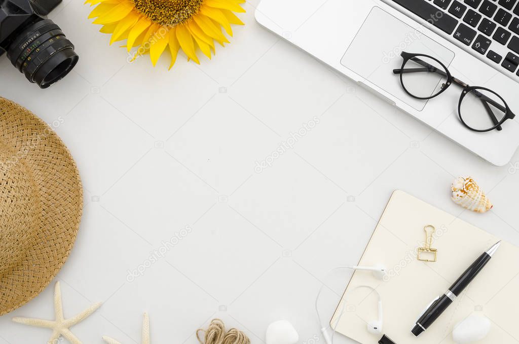 Flat lay mock up. Summer frame from office supplies on white office table with laptop, clips, glasses, notebook, pen, retro photo camera, hat, starfish, sunflower and headphones. Travel mood