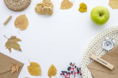 Kuru yaprakları, eşarp, çalar saat, zarf ve yeşil elma sonbahar çerçeveli. Sonbahar düz metni, üstten görünüm mockup yatıyordu