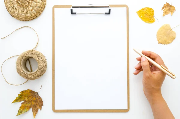 Las manos planas de las niñas laicas sostiene la pluma dorada y las hojas secas de otoño Portapapeles con hoja de papel blanco en blanco. Plantilla de creatividad para letras de mano citas de inspiración sobre el otoño — Foto de Stock