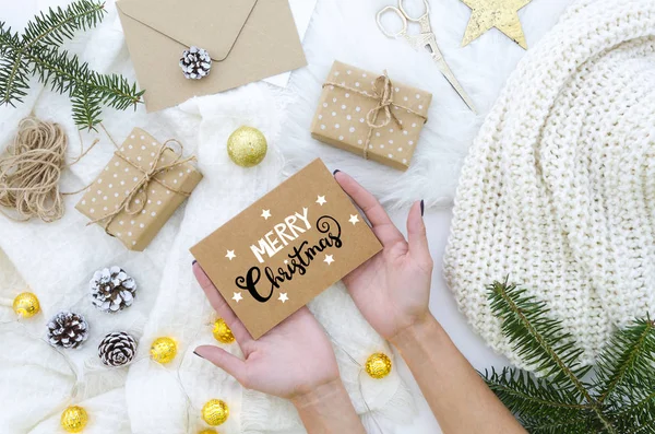 Mãos femininas segurando mão feita Feliz Natal cartão de saudação com letras de mão. Férias de Natal. Composição de Natal. Deitado plano, vista superior . — Fotografia de Stock