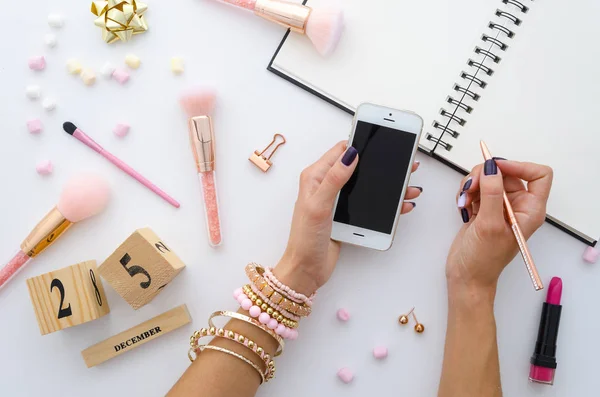 Mesa feminina com doces marshmallow, material de escritório dourado, pincéis de maquiagem rosa e calendário perpétuo 25 de dezembro. A mulher está a planear o dia de Natal. Visão superior com cabeçalho herói espaço cópia — Fotografia de Stock