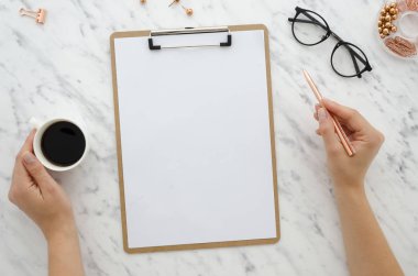 Mockup Pano boş beyaz kağıt levha ile mermer zemin üzerine. Üstten görünüm kadının ellerini tutar altın kalem ve kahve yaratıcılık şablon yazı için. İş, bloglama, eğitim planları yapmak