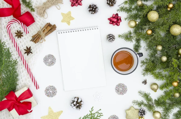 Fundo de Natal com caderno em espiral em branco, ramos de abeto e cones, decorações de Natal, caixas de presente e xícara de chá. Espaço para SMS. Vista superior. Lista de tarefas ou lista de desejos de Natal. deitado plano — Fotografia de Stock