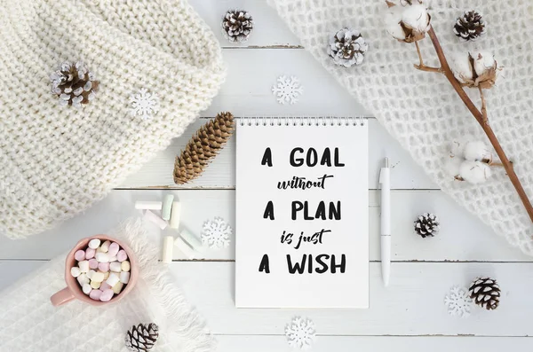 New year motivation a goal without a plan is just a wish. Christmas decorations, knitted blanket, pine cones,cotton flower, marshmello on wooden white background. Flat lay, top view, quote — Stock Photo, Image