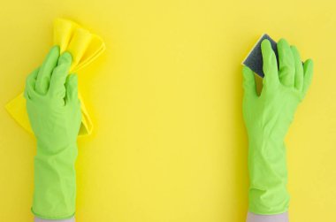 Sünger sarı arka plan üzerinde izole kauçuk eldiven temizlik yeşil el.