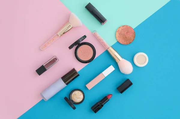 Flat lay Cosméticos para maquiagem, escova, iluminador, corretor, maquiagem, batom, primer, blush on pink, blue and mint tri color vibrant background. Vista superior . — Fotografia de Stock