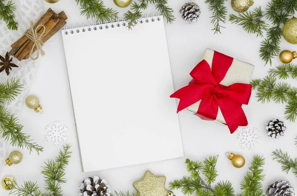 Karácsonyi háttér üres notebook, a fenyő ágak, a dekoráció és a fahéj. Hely, a szöveg. Felülnézet. Karácsonyi to-do lista vagy kívánság oldalra dől. Lapos laikus makett ajándék doboz-val piros szalag — Stock Fotó