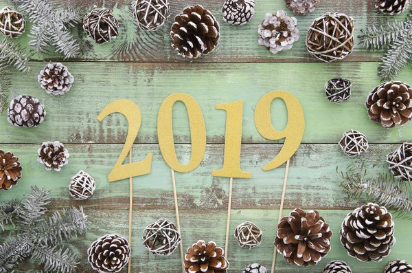 2019 letras de oro sobre fondo de tabla de madera verde con conos de pino y bufanda de punto, tarjeta de felicitación de año nuevo 2019, pancarta, vista superior — Foto de Stock