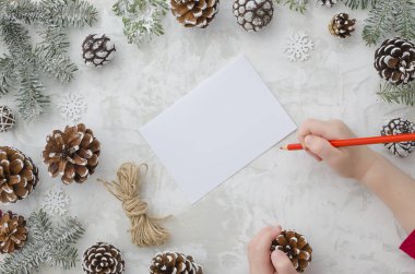 Çocuk Noel Baba'ya mektup yazıyor. Childs'ın personel, kağıt, kırmızı kalem ve Noel süsleri çam kozalakları ve köknar ağacı arka plan sayfası. Yeni yıl ve Noel kavramı. Üstten görünüm