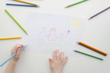 Bir çocuğun ailesi ile kalemler çizer. Childs çizim ve renkli kalemler. Beyaz kağıt üzerine çizim aile. Üstten görünüm. Düz yatıyordu