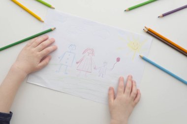 Bir çocuğun ailesi ile kalemler çizer. Childs çizim ve renkli kalemler. Beyaz kağıt üzerine çizim aile. Üstten görünüm. Düz yatıyordu