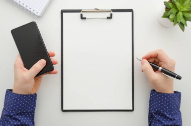 Belgelerle çalışma ve bir cep telefonu kullanarak iş adamı. Pano mockup şablonu belge, finansal raporlar, özgeçmiş, kısa, form, sözleşme. Üstten görünüm. Düz yatıyordu iş kavramı