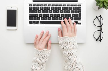 Kadının el laptop tuş takımında yazarak üstten görünüm beyaz ofis masaüstü boş smartphone, gözlük ve dekoratif bitki ile yerleştirilir. En az düz lay kadar alay