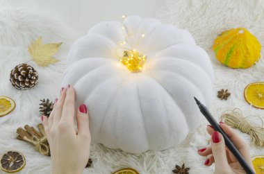 Beyaz boyalı kabak mockup atr için el yazısı. Kadın bir kaligrafi fırçası kalem ile beyaz balkabağına çizer. Üstten görünüm