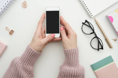 Kadınsı çalışma alanı mockup smartphone eller, defter, Gözlük, Not defteri, kalem ve ofis malzemeleri ile. Düz yatıyordu, en iyi görünümü