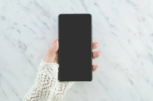 Kvinna hand håller svart telefonen på marmor bakgrund. Smartphone mockup — Stockfoto